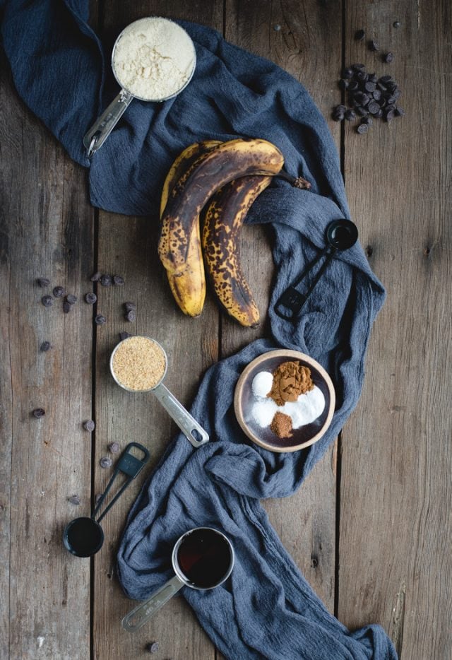 Brown bananas and other banana bread ingredients on a dark wooden background
