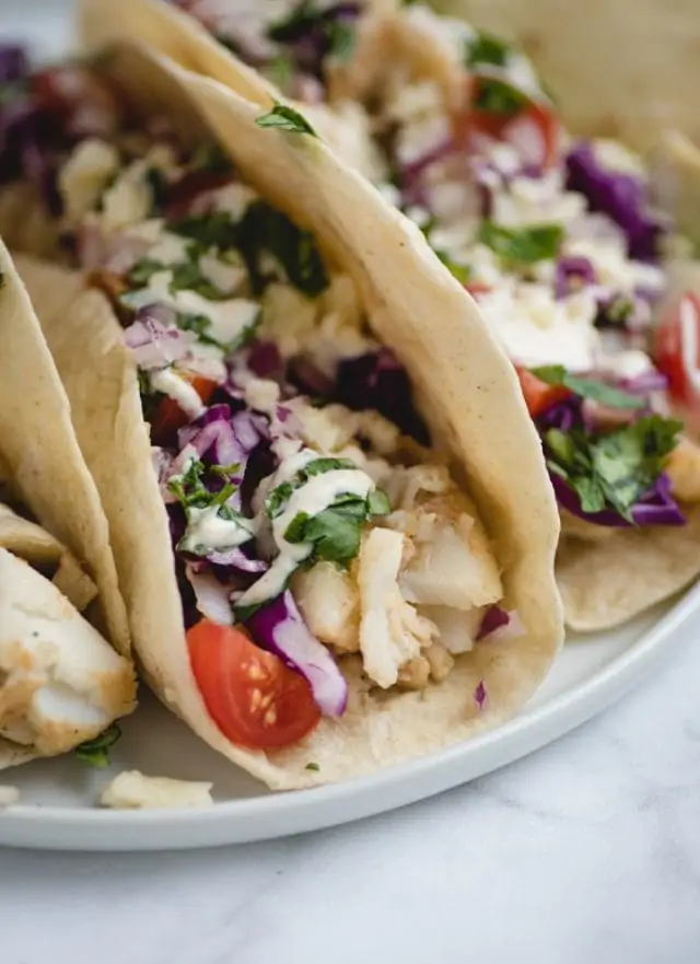 very close up picture of fish tacos on a white plate