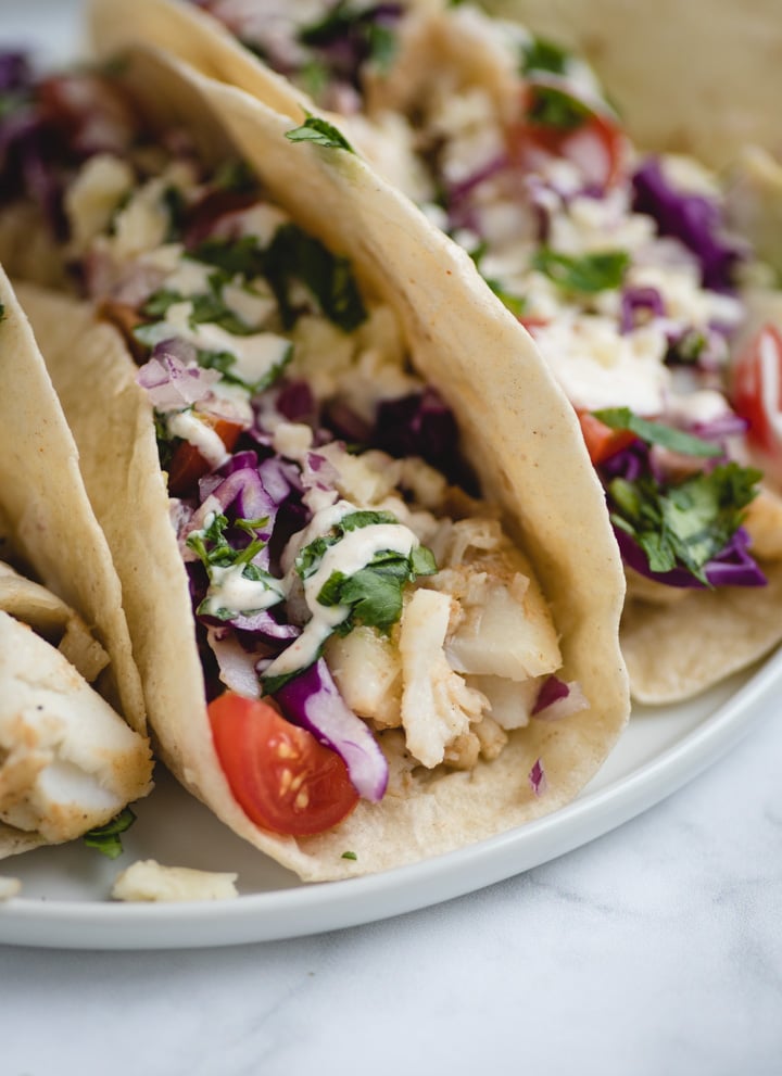 very close up picture of fish tacos on a white plate