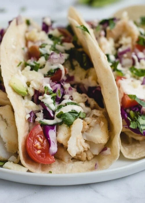 Close up picture of fish tacos on a white plate