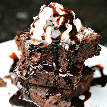 Stack of brownies topped with ice cream and chocolate syrup