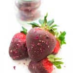 stack of chocolate dipped strawberries dusted with crushed rose petal on a white background