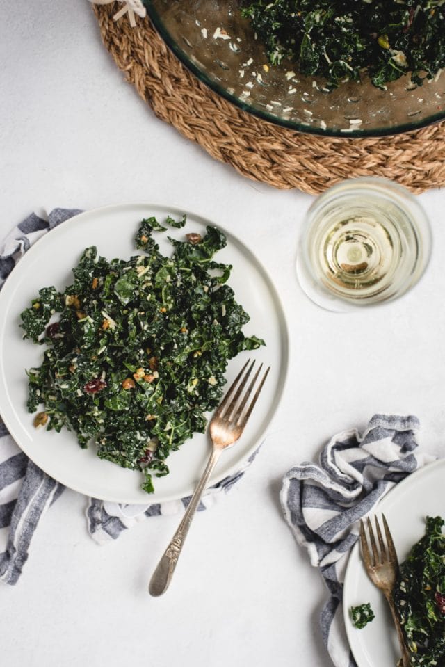 close up picture of white plate with kale salad and white wine