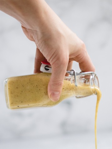 hand holding and pouring jar of vinaigrette