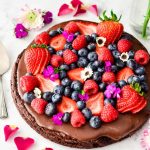 chocolate pizza topped with berries on white background