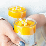 hands holding two servings of tapioca pudding with mango