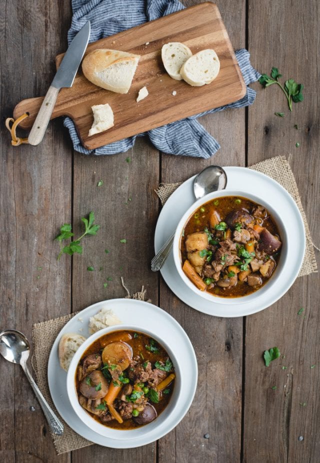 overhead picture of table with two bowls of beef stew and a loaf of bread