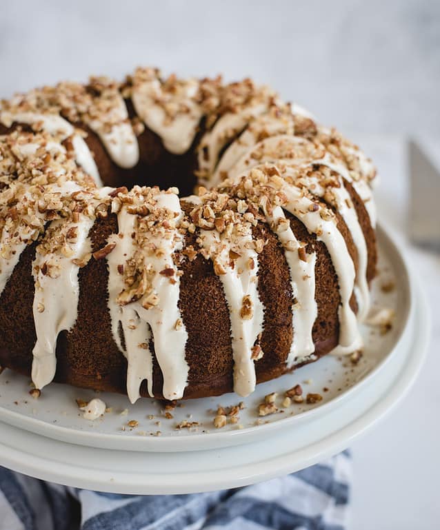 banana bundt cake with cream cheese frosting and nuts sprinkled on top 