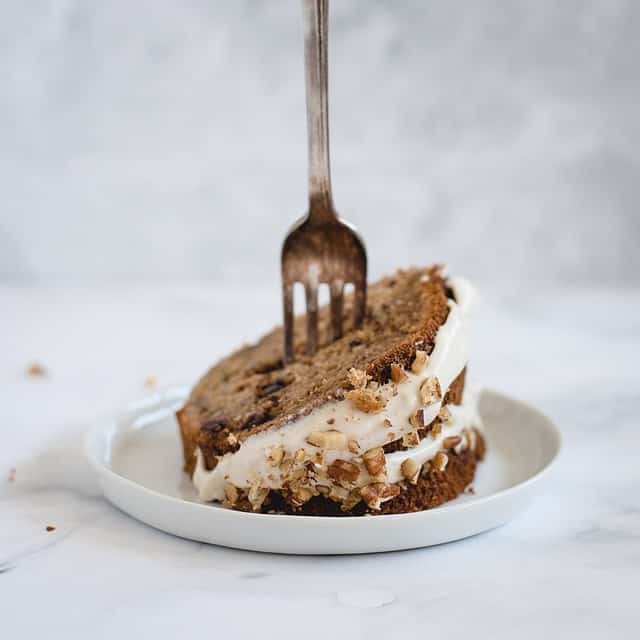 slice of banana bundt cake on a white plate with a fork sticking straight up into it