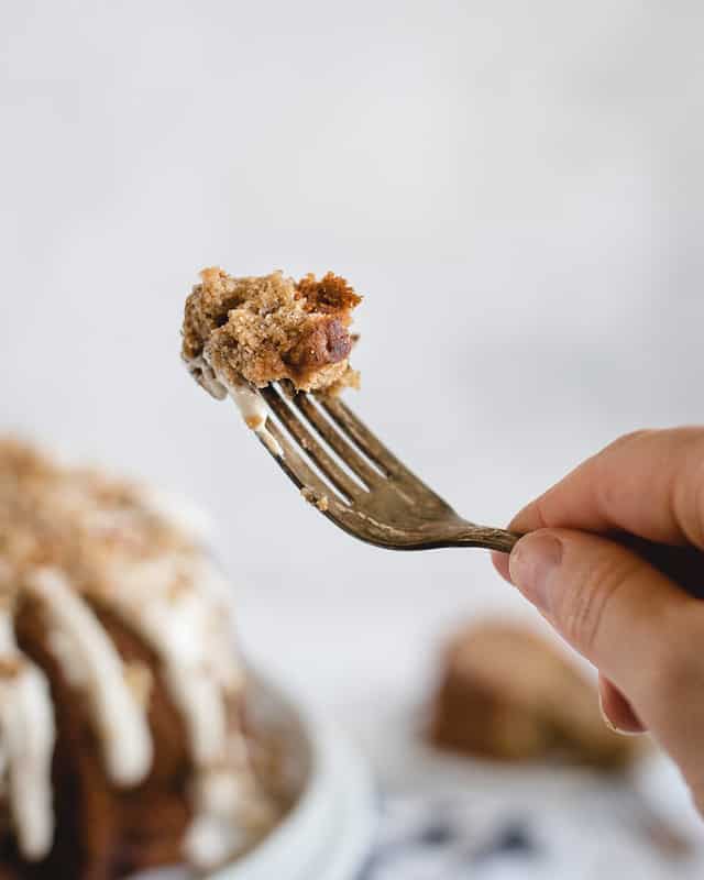 Fork holding up a bite of cake on it against a white background