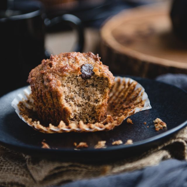 Close up picture of almond flour banana muffin on a black plate with bite taken out of it
