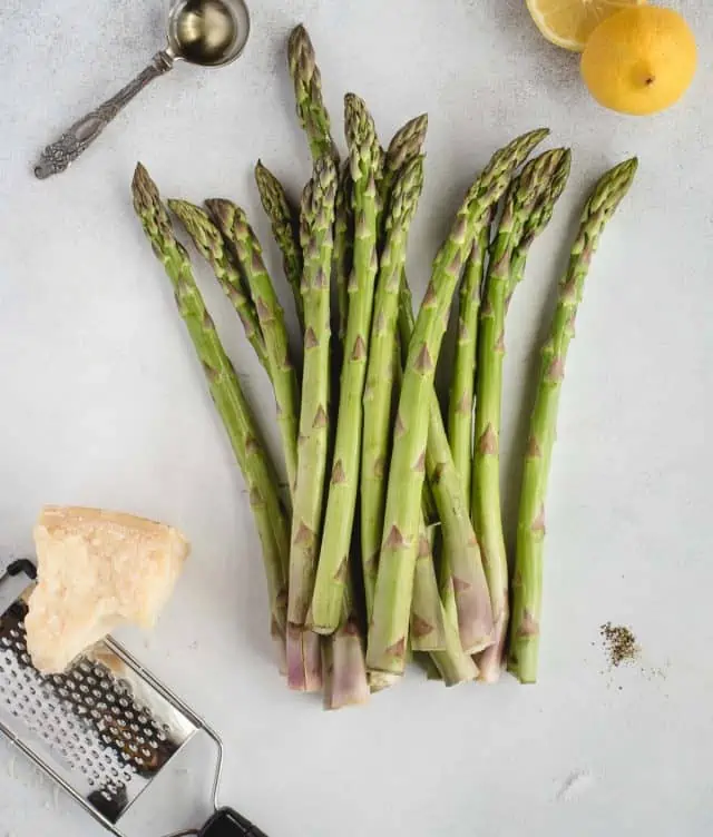 ingredients for air fryer asparagus laid out on a gray background
