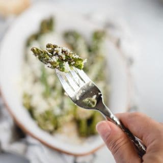 hand holding a fork with asparagus tips on it