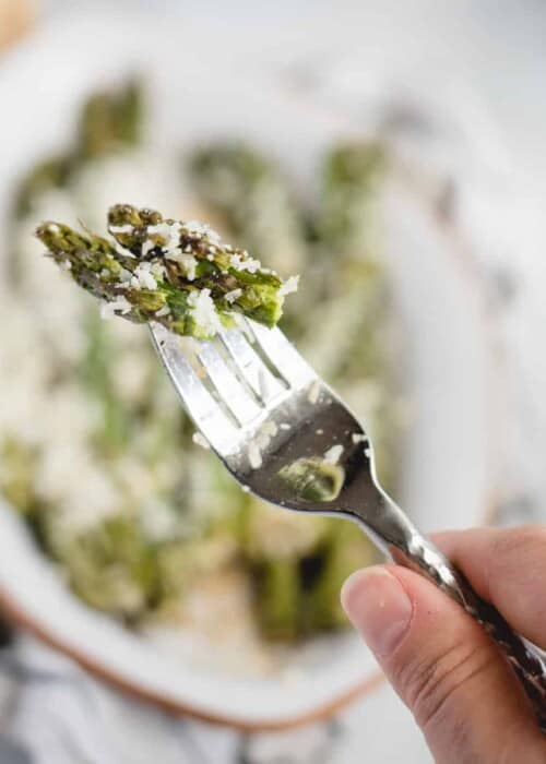 hand holding a fork with asparagus tips on it