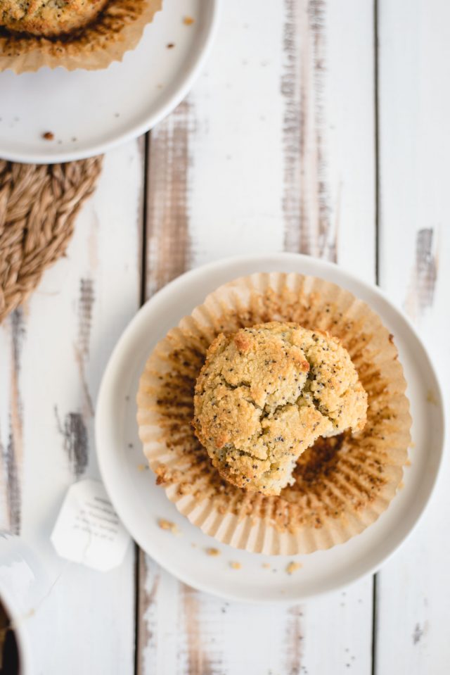 close up overhead picture of an almond poppy seed muffin on a white plate and background