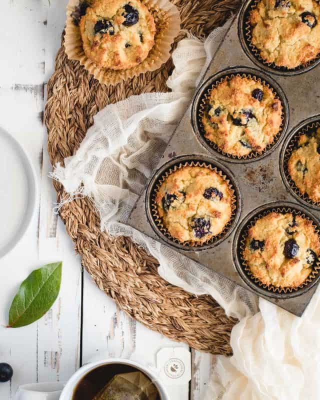 Close up overhead picture of blueberry muffins in a tin on a white background