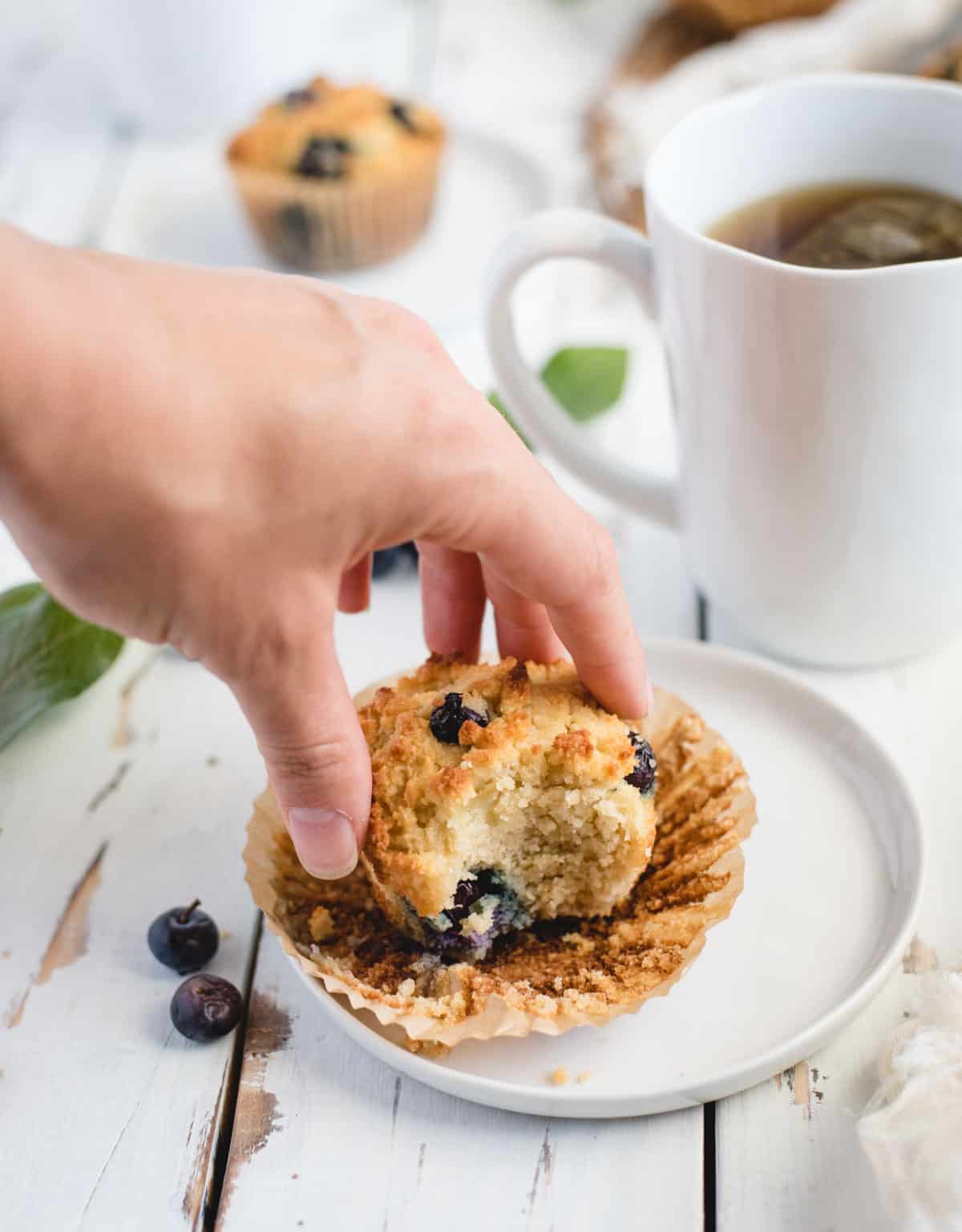 Hand reaching out to grab soft muffin off of a plate
