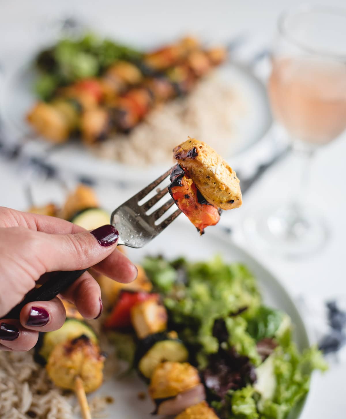 hand holding a bite of chicken and red pepper up on a fork