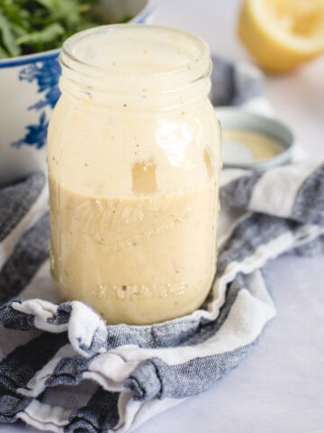 Close up picture of mason jar with lemon dressing on a blue and white towel