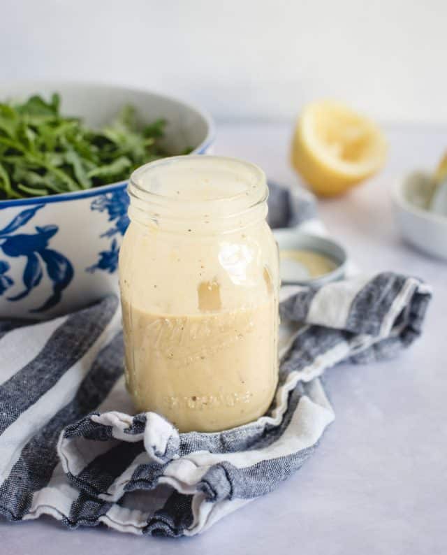 Mason jar with lemon dressing on a blue and white towel