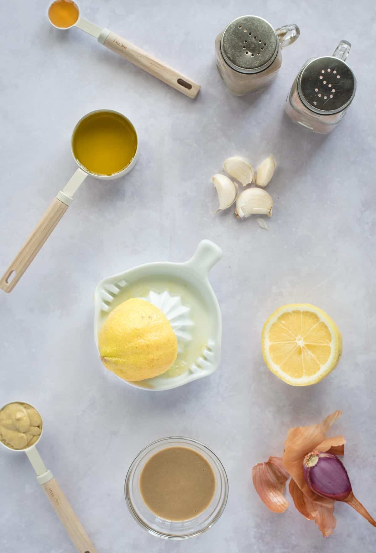 scattered ingredients laid out on a gray background for making salad dressing.