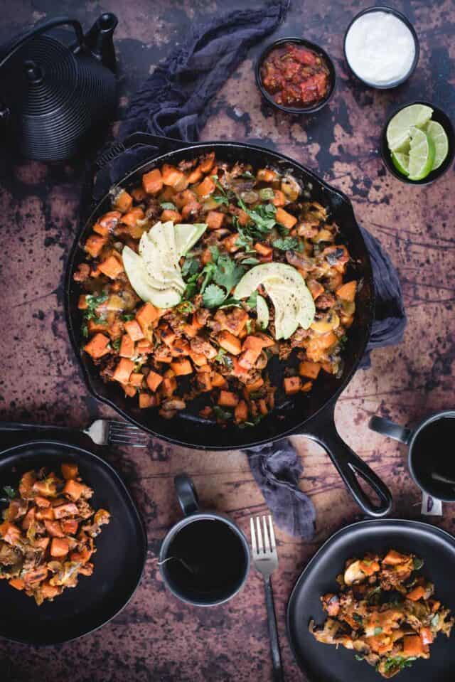 overhead picture of chorizo sweet potato skillet on a dark background with servings on two plates
