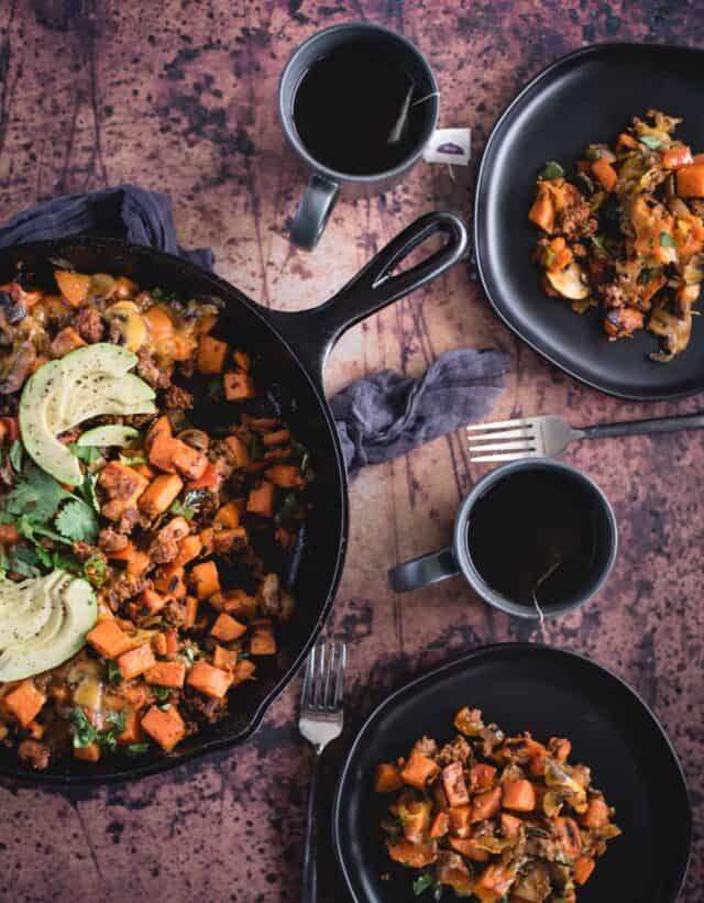 overhead picture of southwest sweet potato skillet on a dark background with tea and two breakfast servings