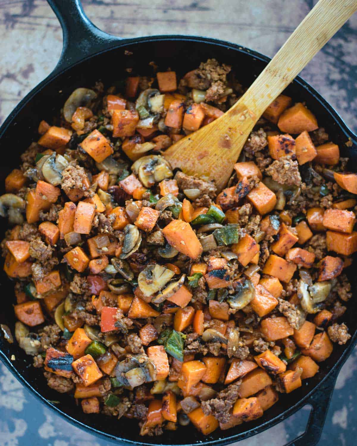 cooked sweet potato, chorizo, mushrooms and peppers mixed together in a cast iron skillet from overhead