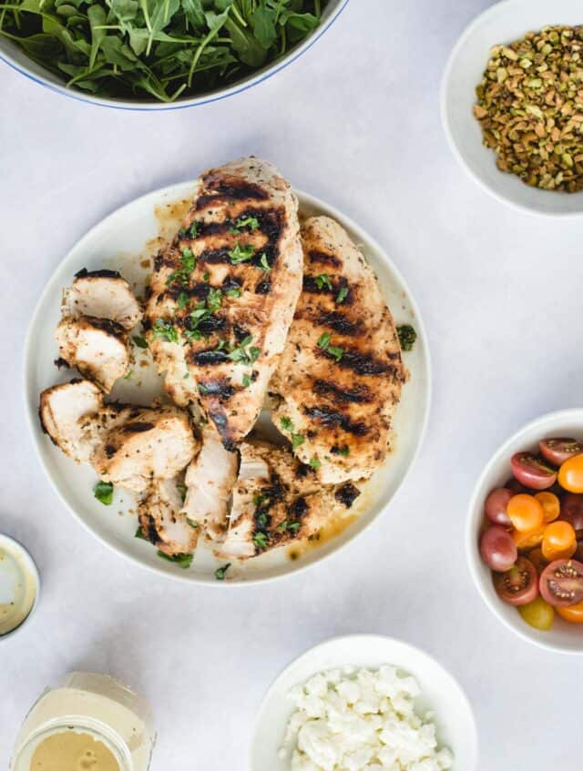 over head picture of plate with grilled chicken and other salad ingredients on a white background 