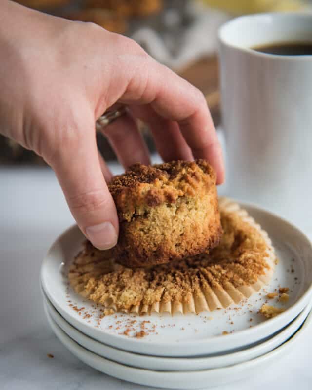hand grabbing coffee cake muffin from the side off of a small plate