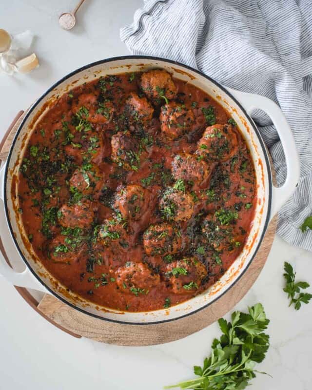 Overhead picture of pan of meatballs in sauce on a white backdrop