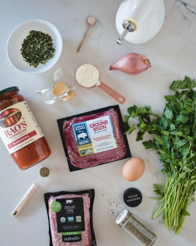 flat lay of ingredients needed to make bison meatballs on marble backdrop