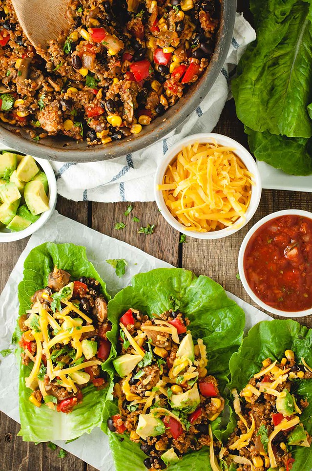 Overhead picture of taco vegetarian lettuce wraps next to a pan with the quinoa black bean filling in it and toppings