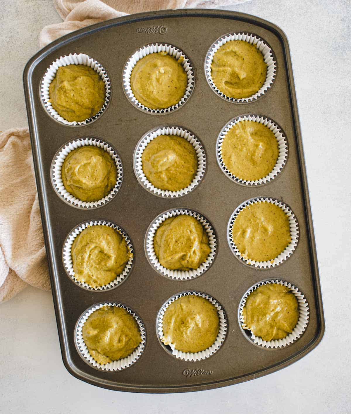 Unbaked green muffin batter in muffin tray