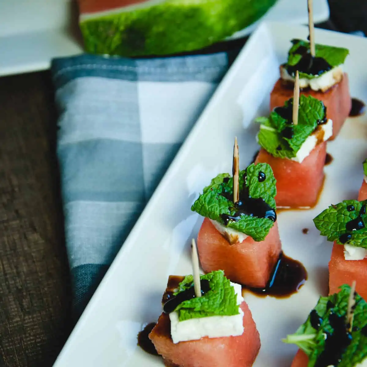 watermelon, feta and mint on toothpicks topped with a balsamic glaze drizzle