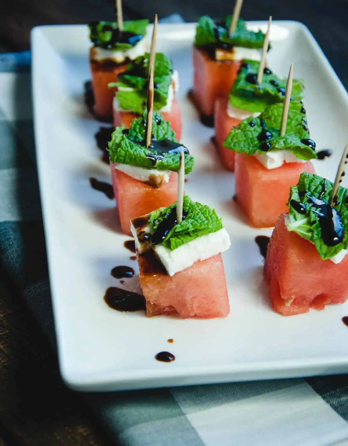 watermelon cubes, feta and mint on toothpicks served on a plate