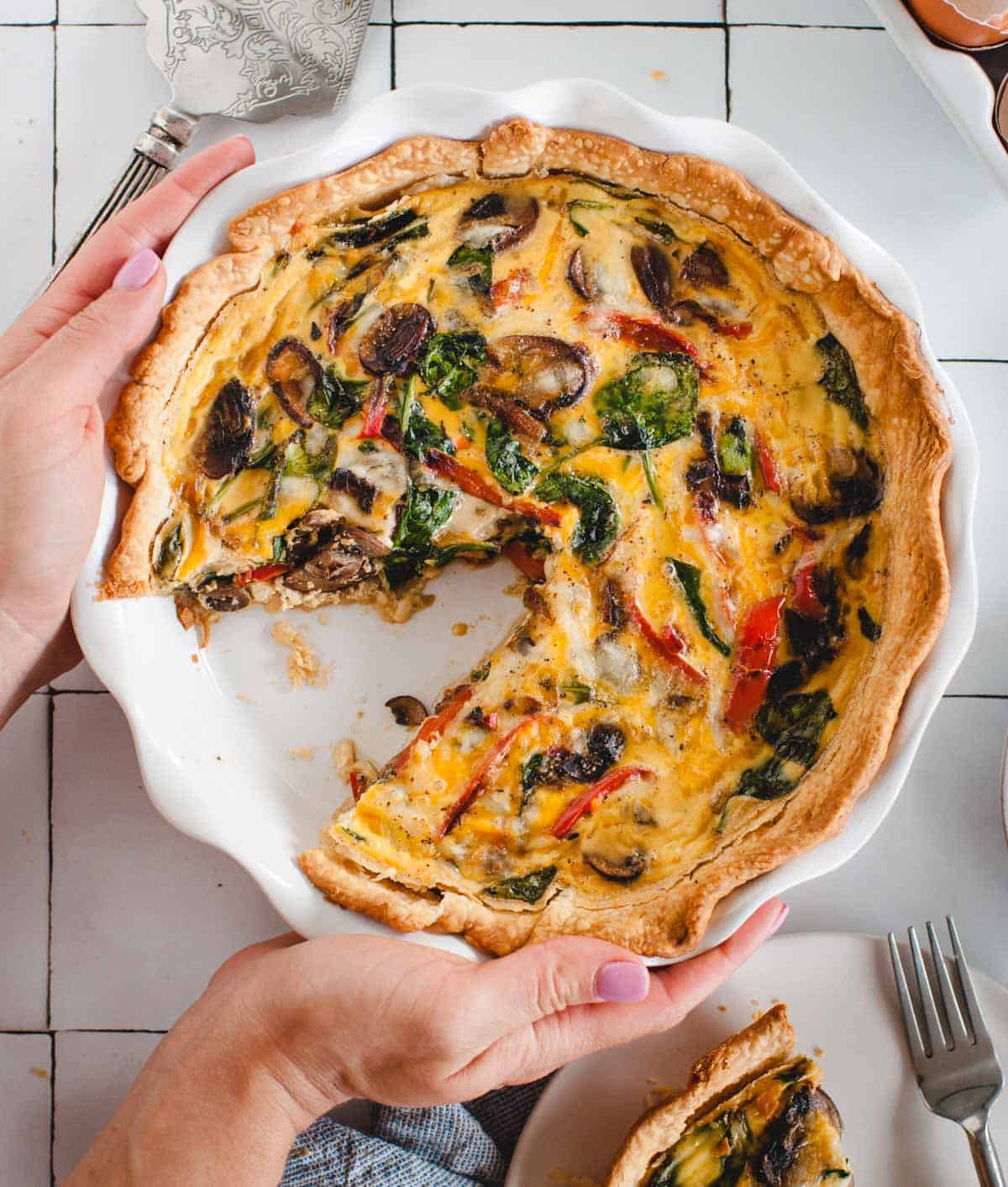 hands setting a quiche down on a tabletop