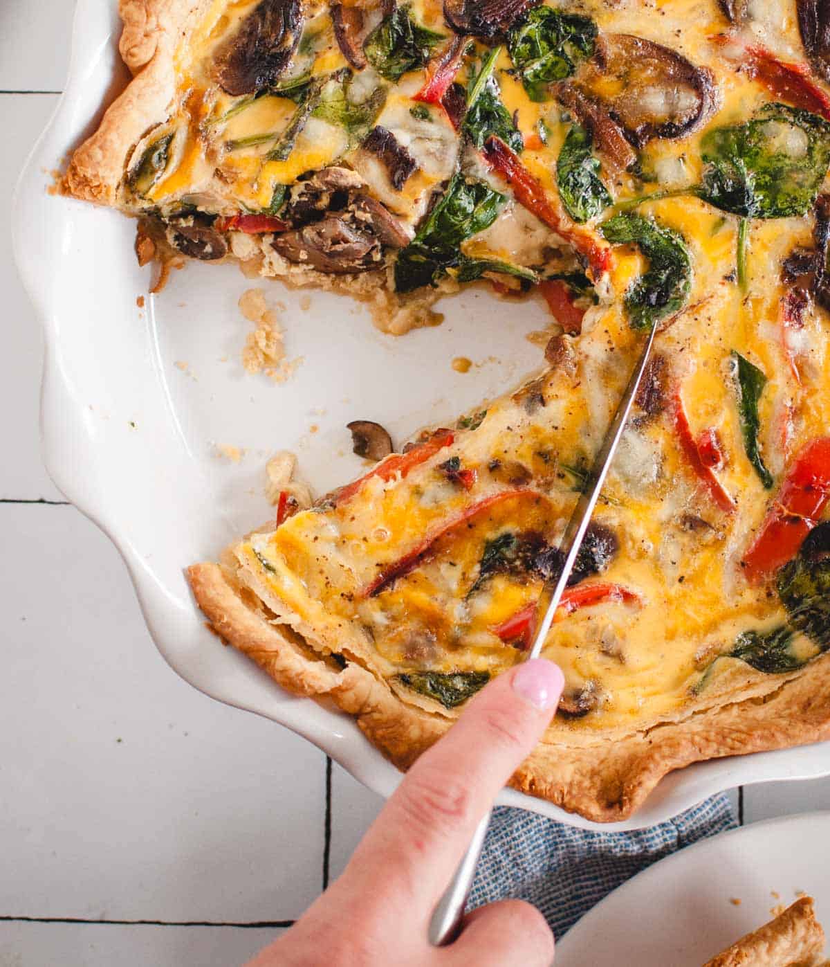 veggie quiche being sliced with a knife