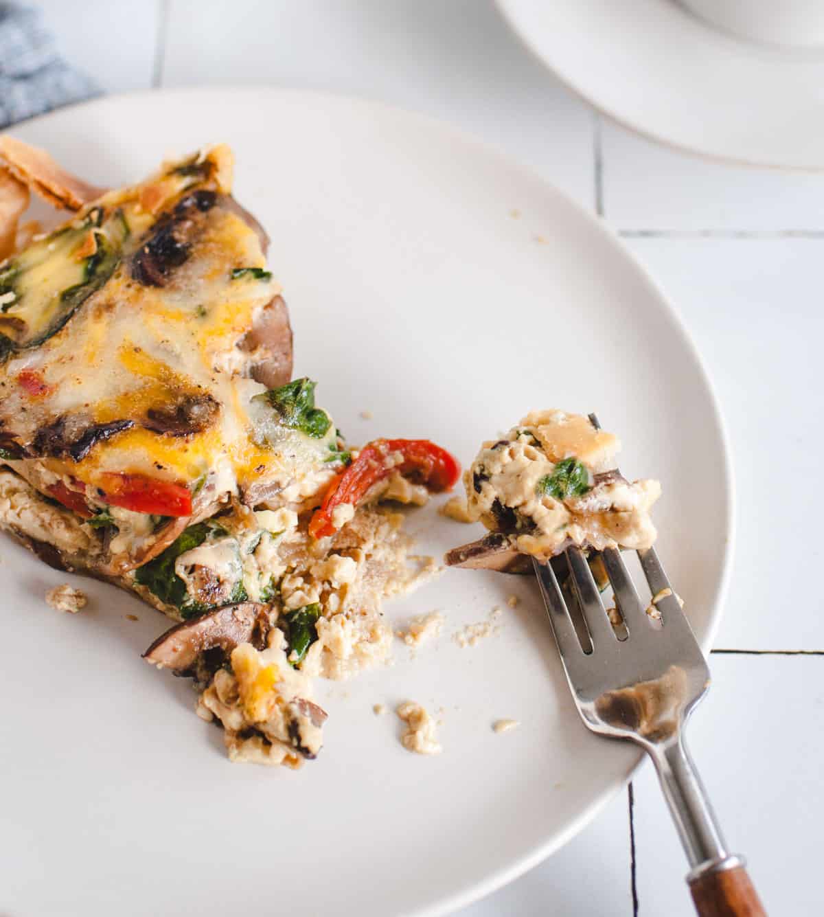 plate with slice of quiche and a fork with a bite on it