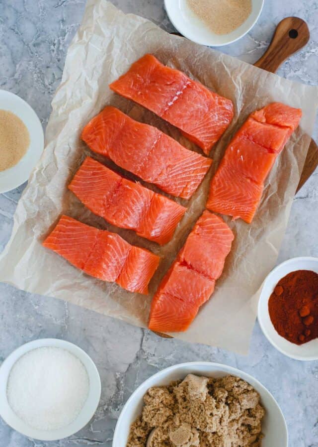 fresh salmon, salt, brown sugar, and spices laid out in bowls from overhead angle
