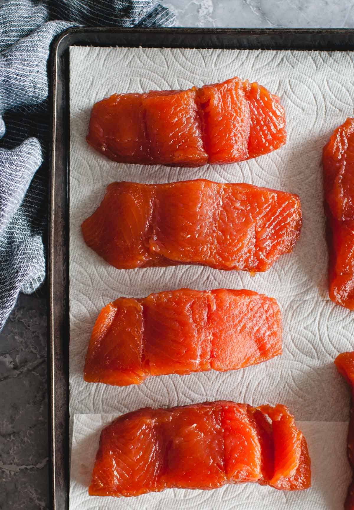 pre-cooked brined salmon laid out on a tray with paper towels