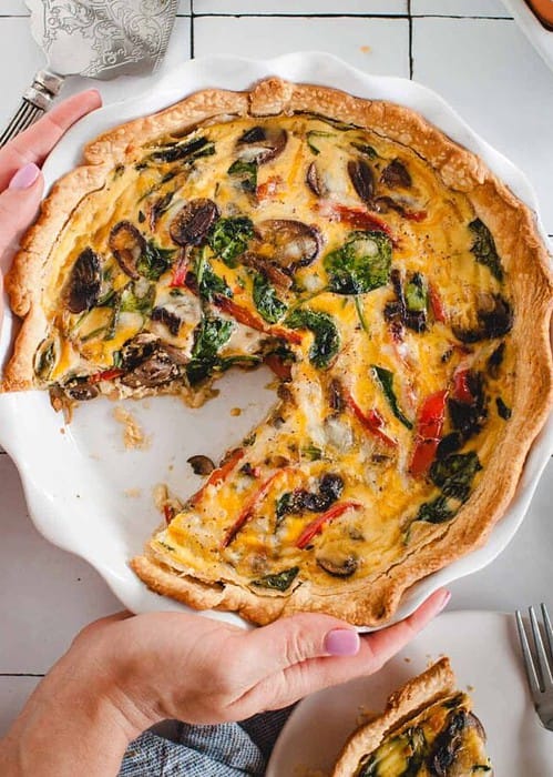 hands setting a quiche down on a tabletop