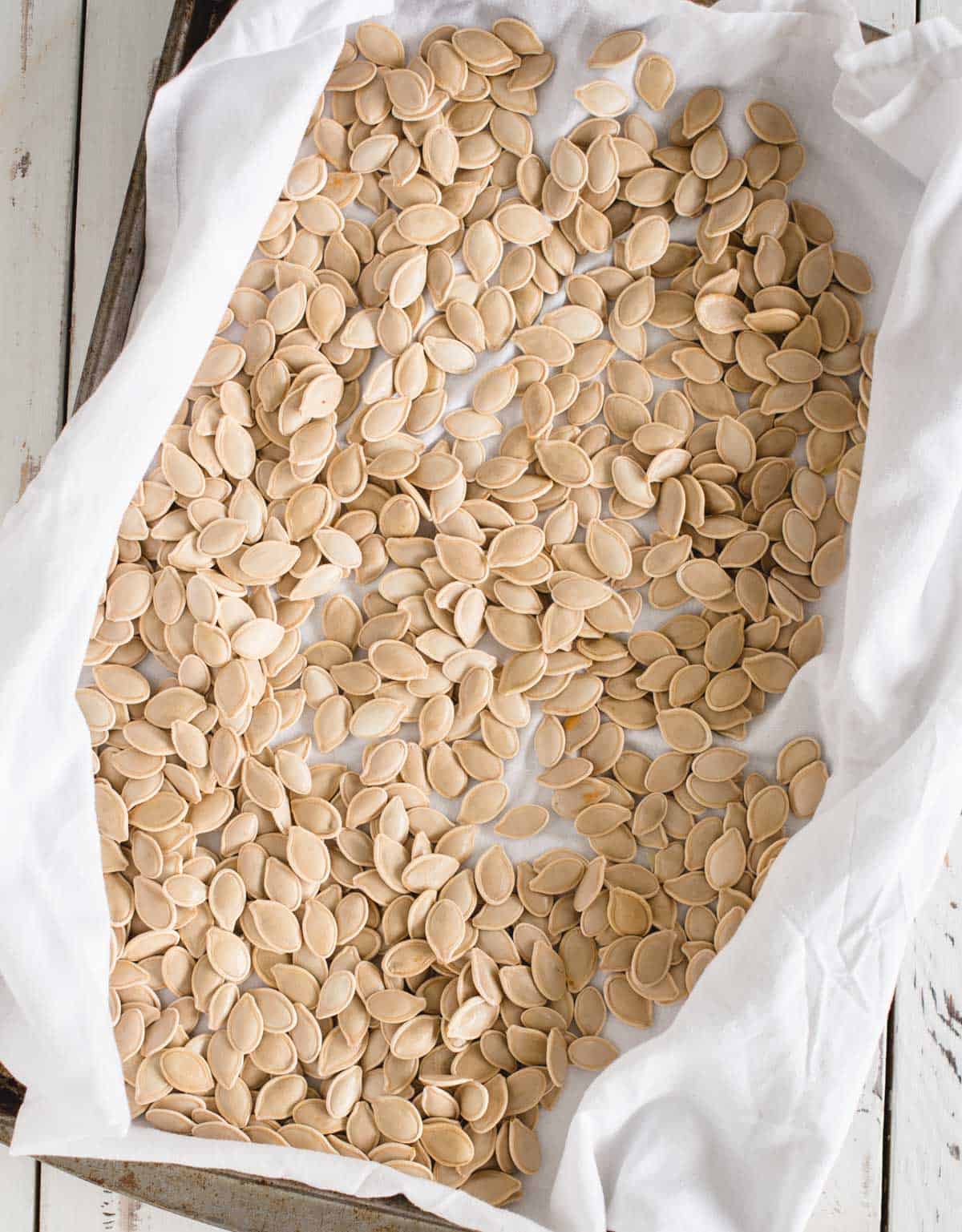 raw pumpkin seeds drying on a kitchen towel