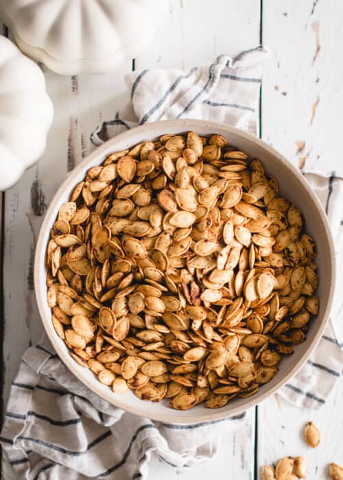 bowl of roasted pumpkin seeds on white background