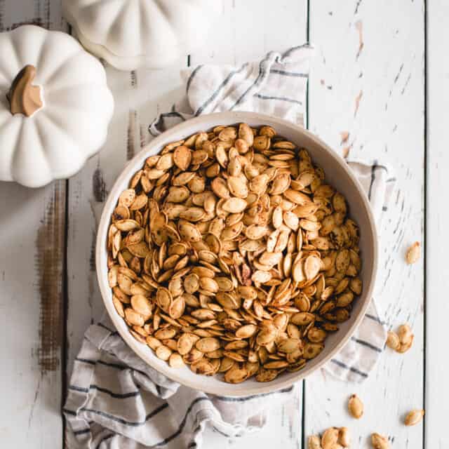 bowl of roasted pumpkin seeds on white background