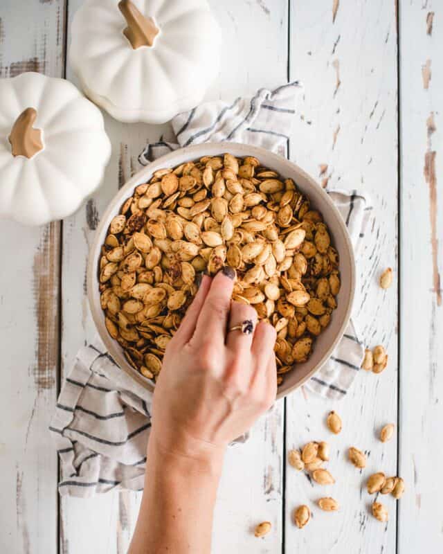 Hand grabbing pumpkin seeds from a bowl