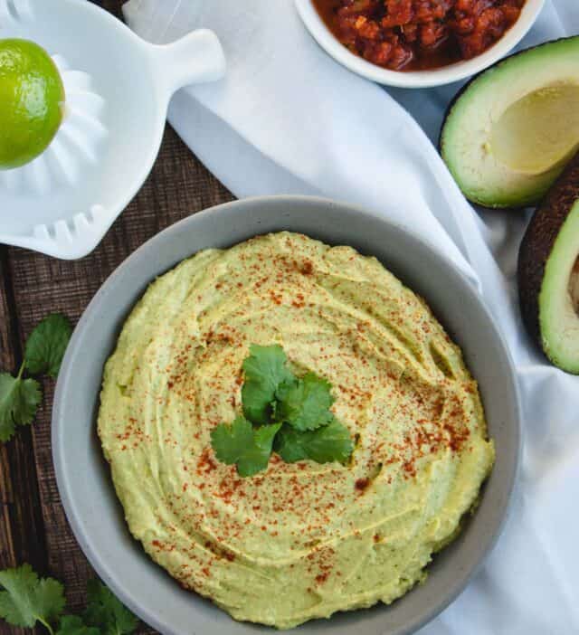 overhead vertical of avocado hummus with salsa next to it