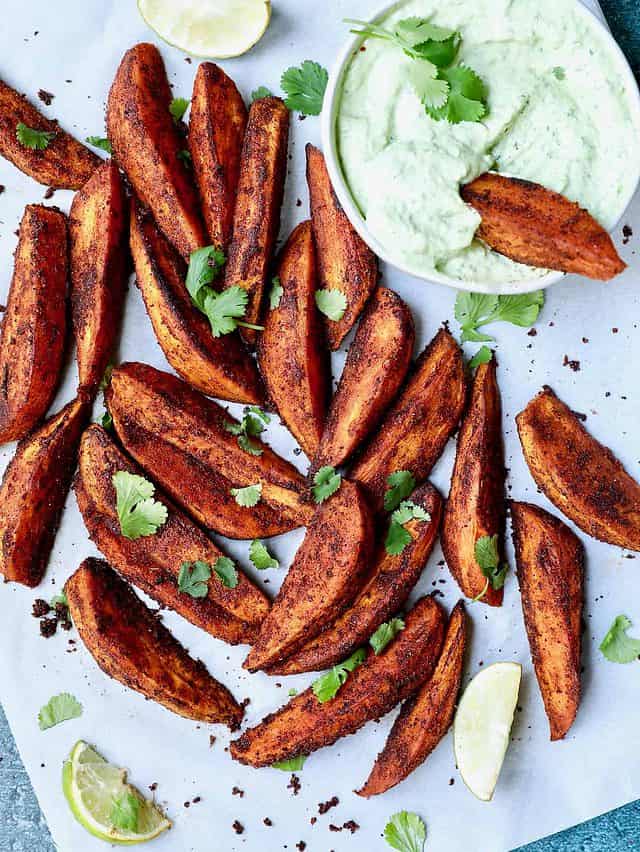 sweet potato wedges laid out flat next to green dipping sauce