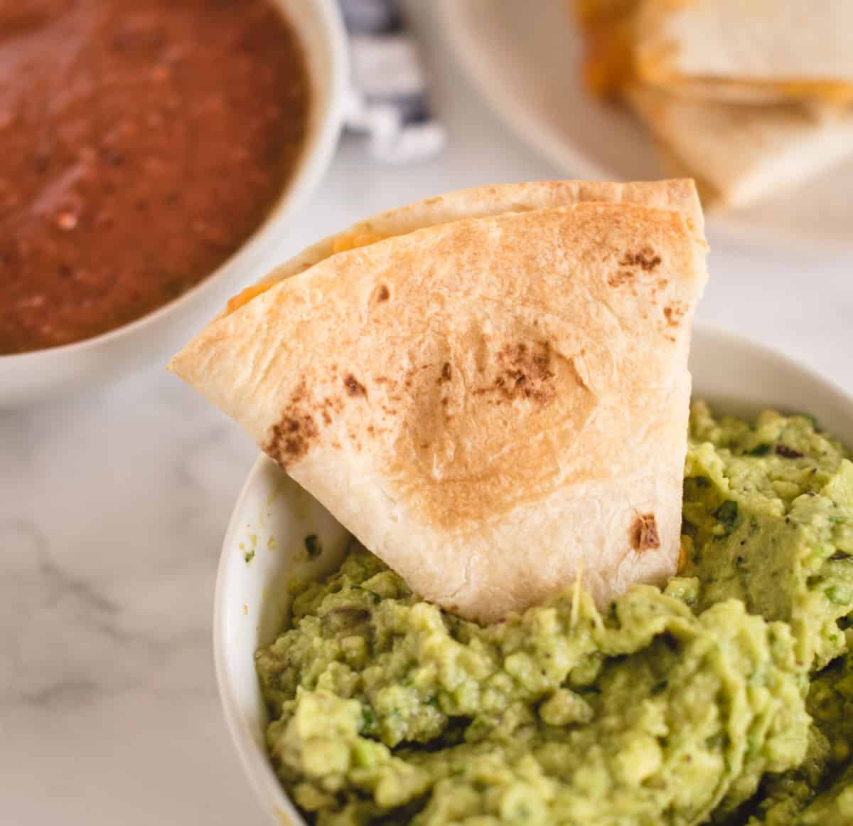 cheese quesadilla dipped into bowl of guacamole