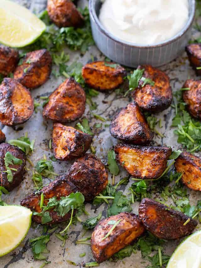 roasted potatoes on a dark pan with herbs